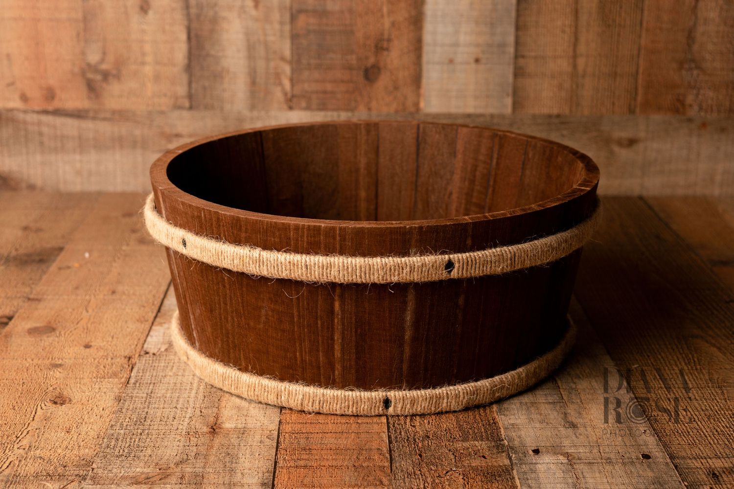 Dark wooden barrel bowl with burlap rope trim on rustic wood floor background, perfect for newborn photography prop.