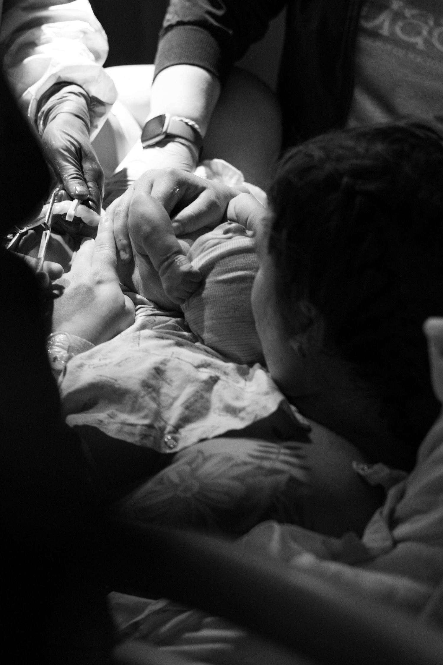 Medical staff and a partner hold hands with a mother during childbirth in a hospital setting.