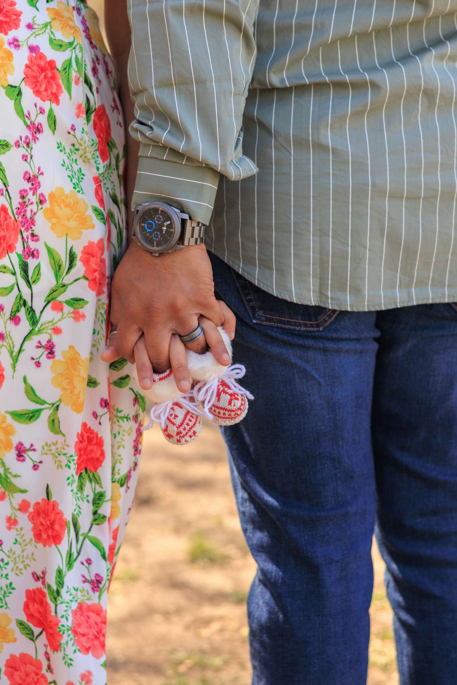 Close-up of expecting couple holding tiny baby shoes together during an outdoor maternity session.