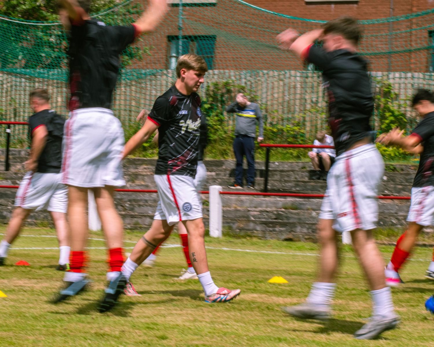 Young footballers warming up on a grass pitch during pre-match training.