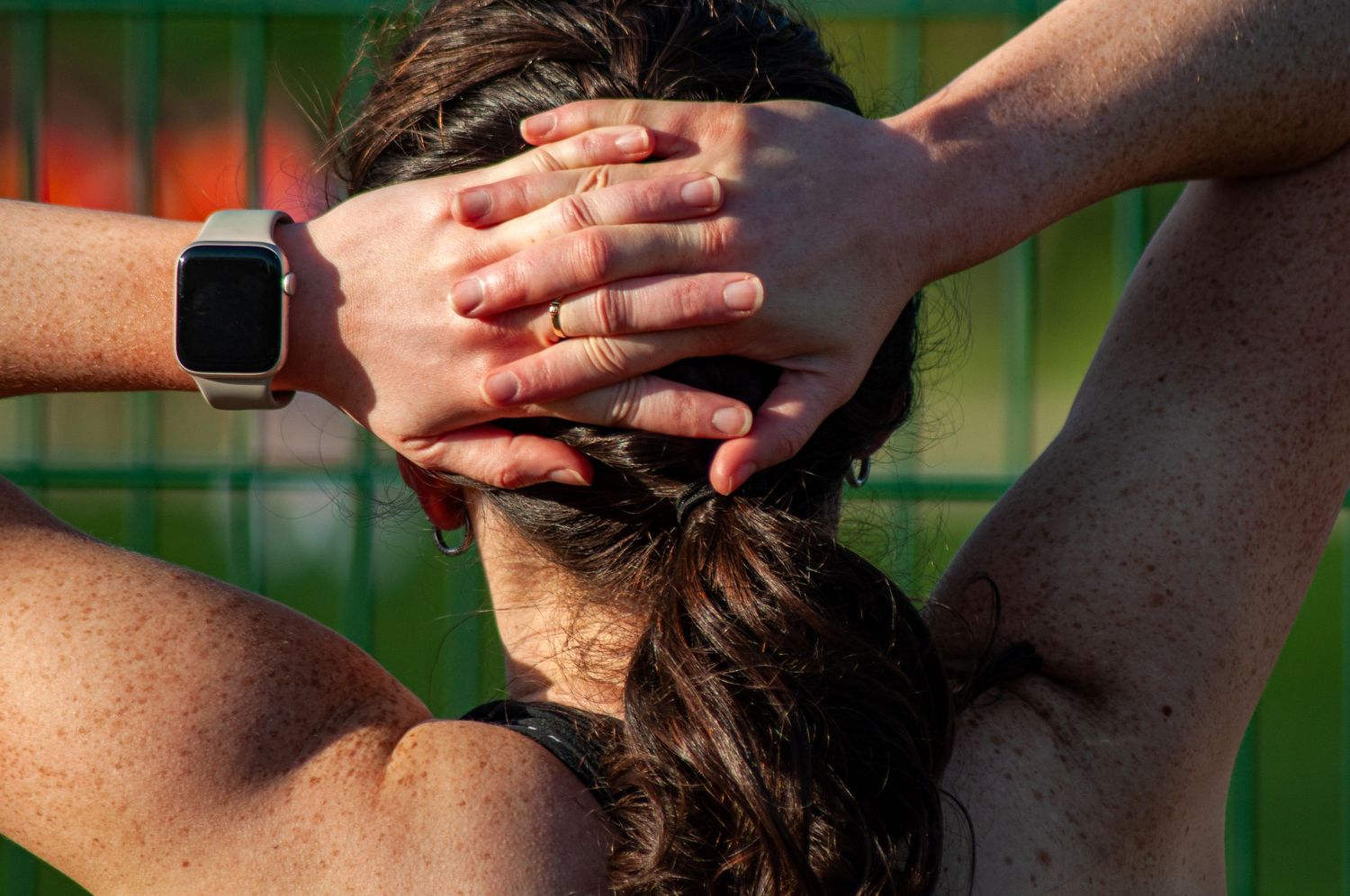 Female athlete with hands clasped behind her head wearing an Apple Watch after a run.