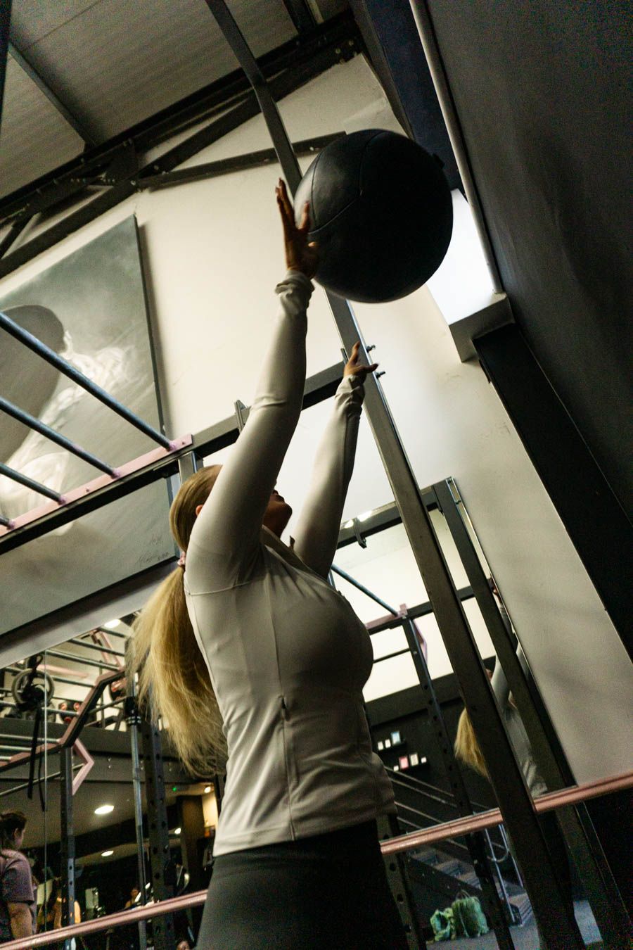 Woman throwing a medicine ball overhead in a gym workout session.