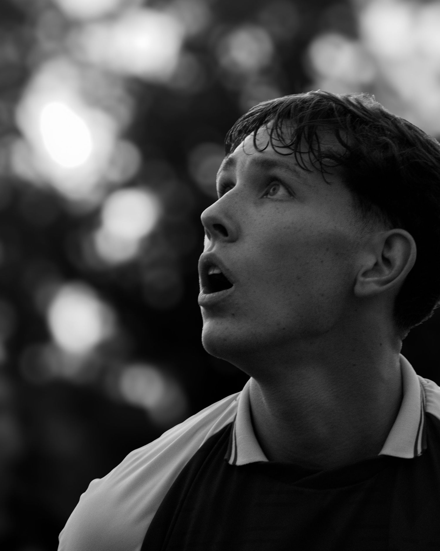 Black and white close-up of a young male soccer player looking up intensely during a match.