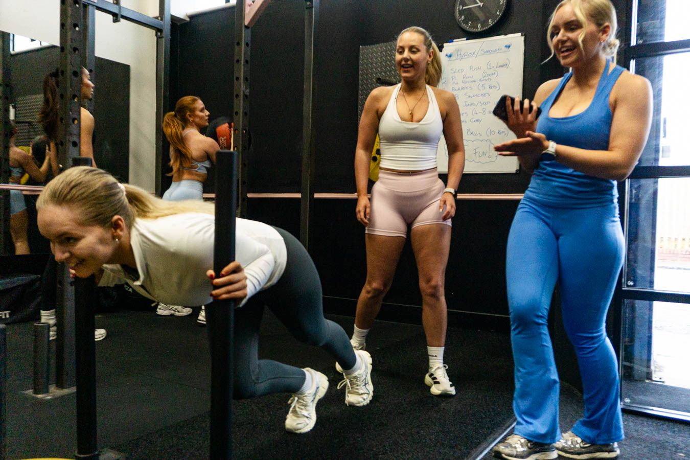 Women working out together at a CrossFit gym with pull-up bars.
