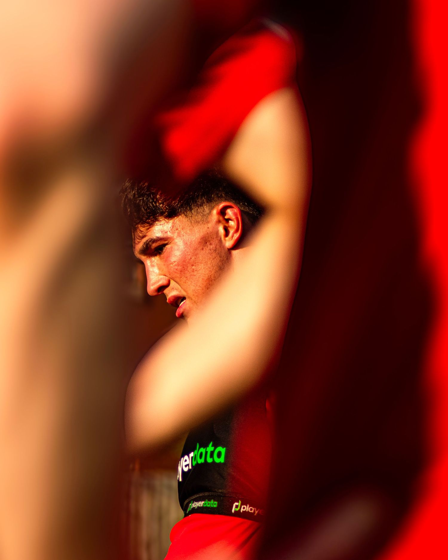 Close-up of a focused young footballer in red kit during a match.