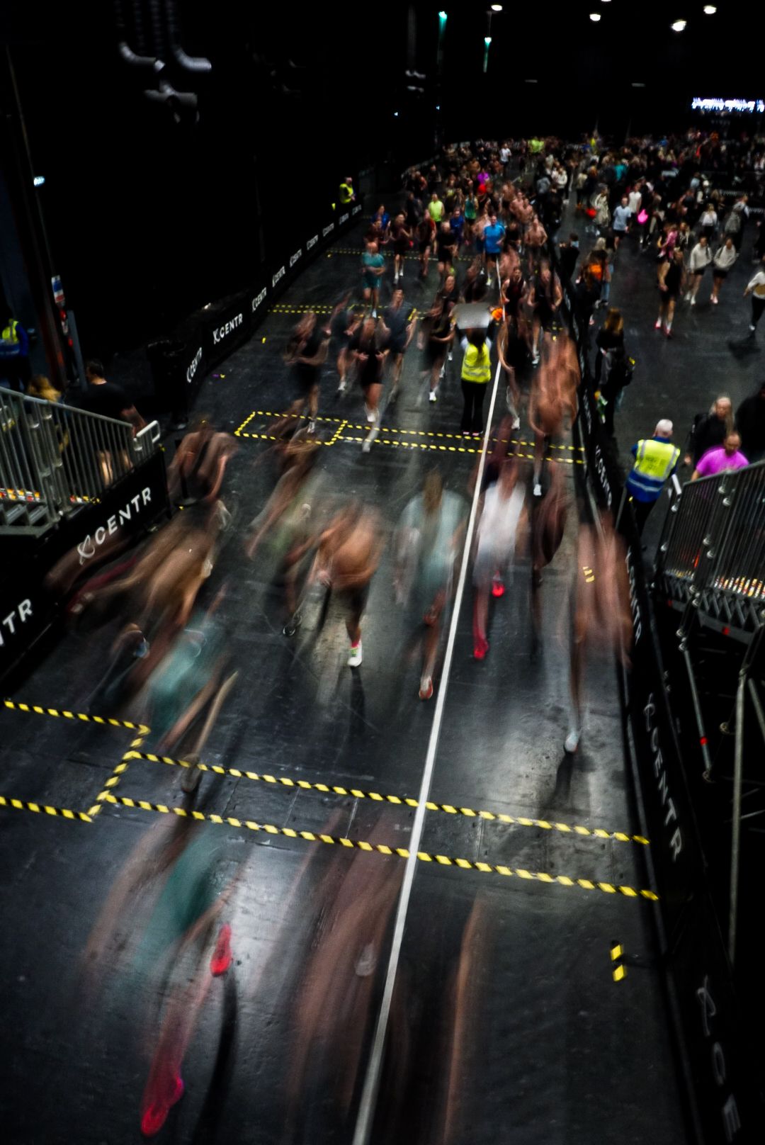 Motion blur aerial shot of large crowd of athletes running during an indoor fitness competition event.