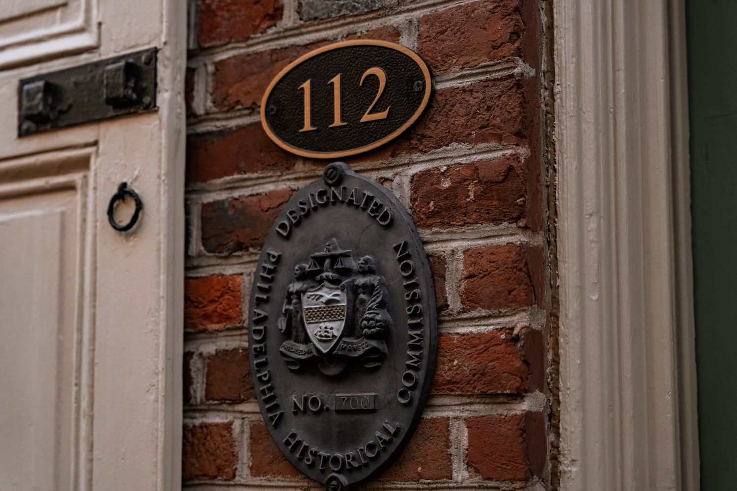 A historic building entrance at 112 features a brass designated historic district plaque on a red brick wall.