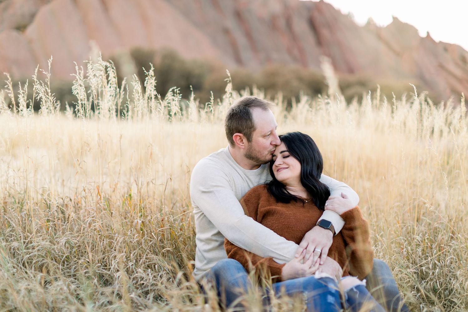 A married couple sitting in a field of tall grass