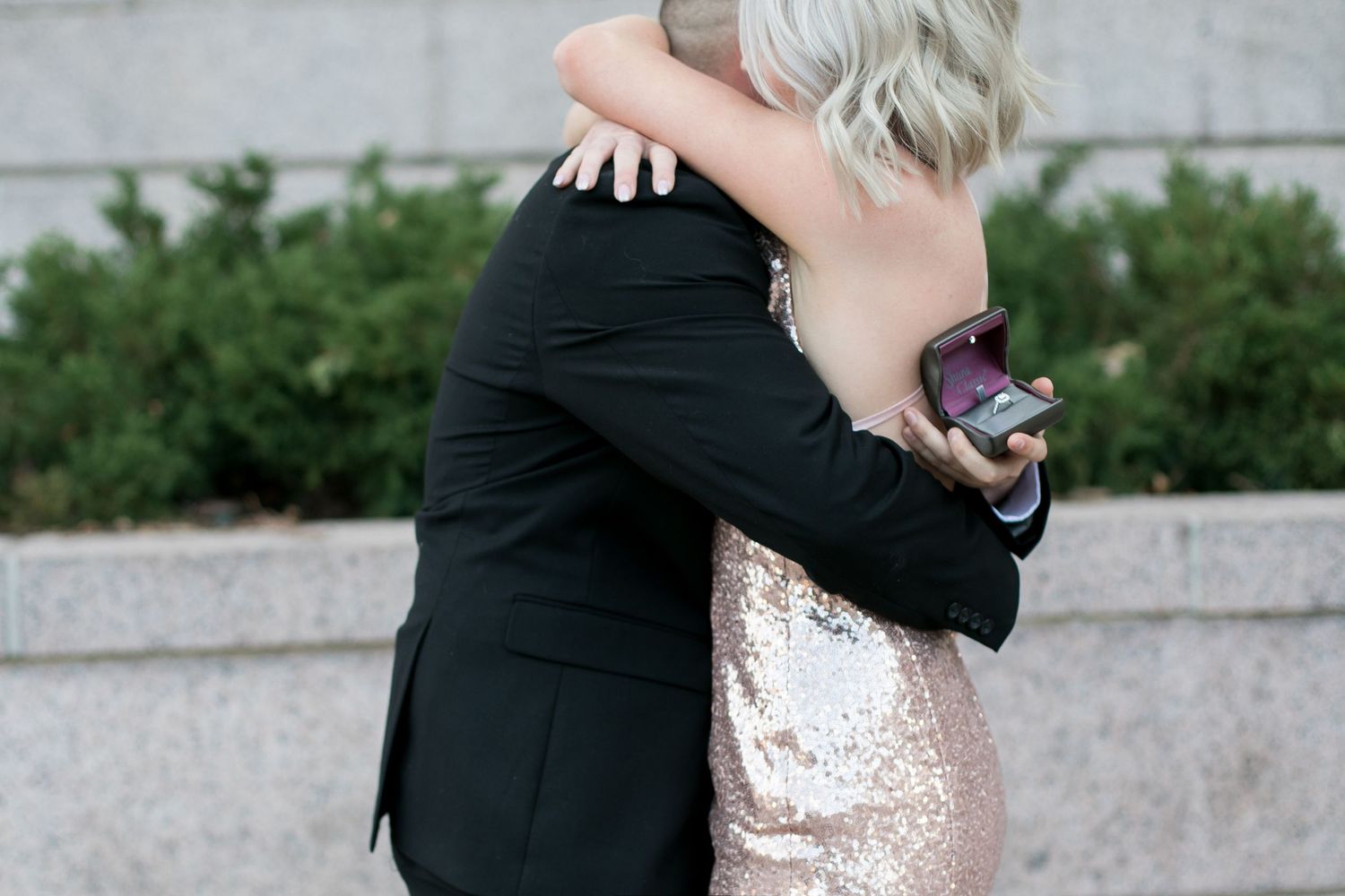 Close up of the ring while a couple hugs after their proposal