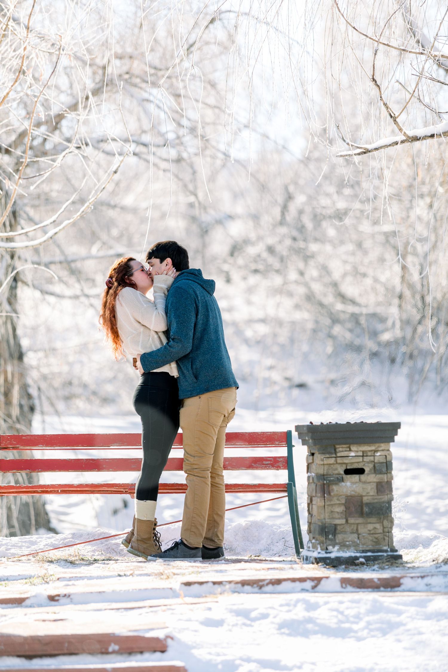 A couple kissing in the snow after their proposal