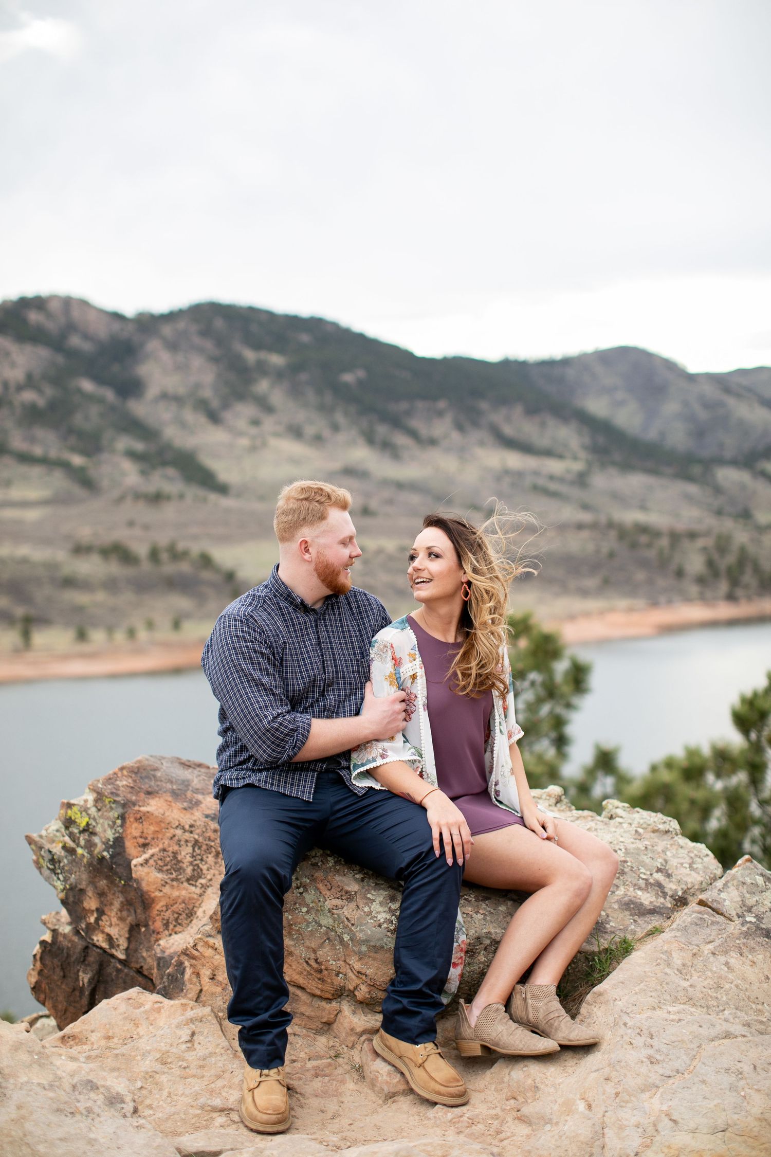 couple sitting on rock during engagement photos Horsetooth Reservoir Fort Collins Colorado
