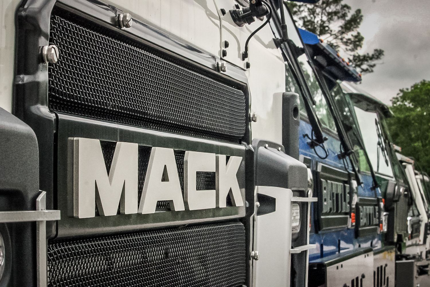 Close-up detail shot of chrome Mack truck logo on front grille of large commercial vehicle.