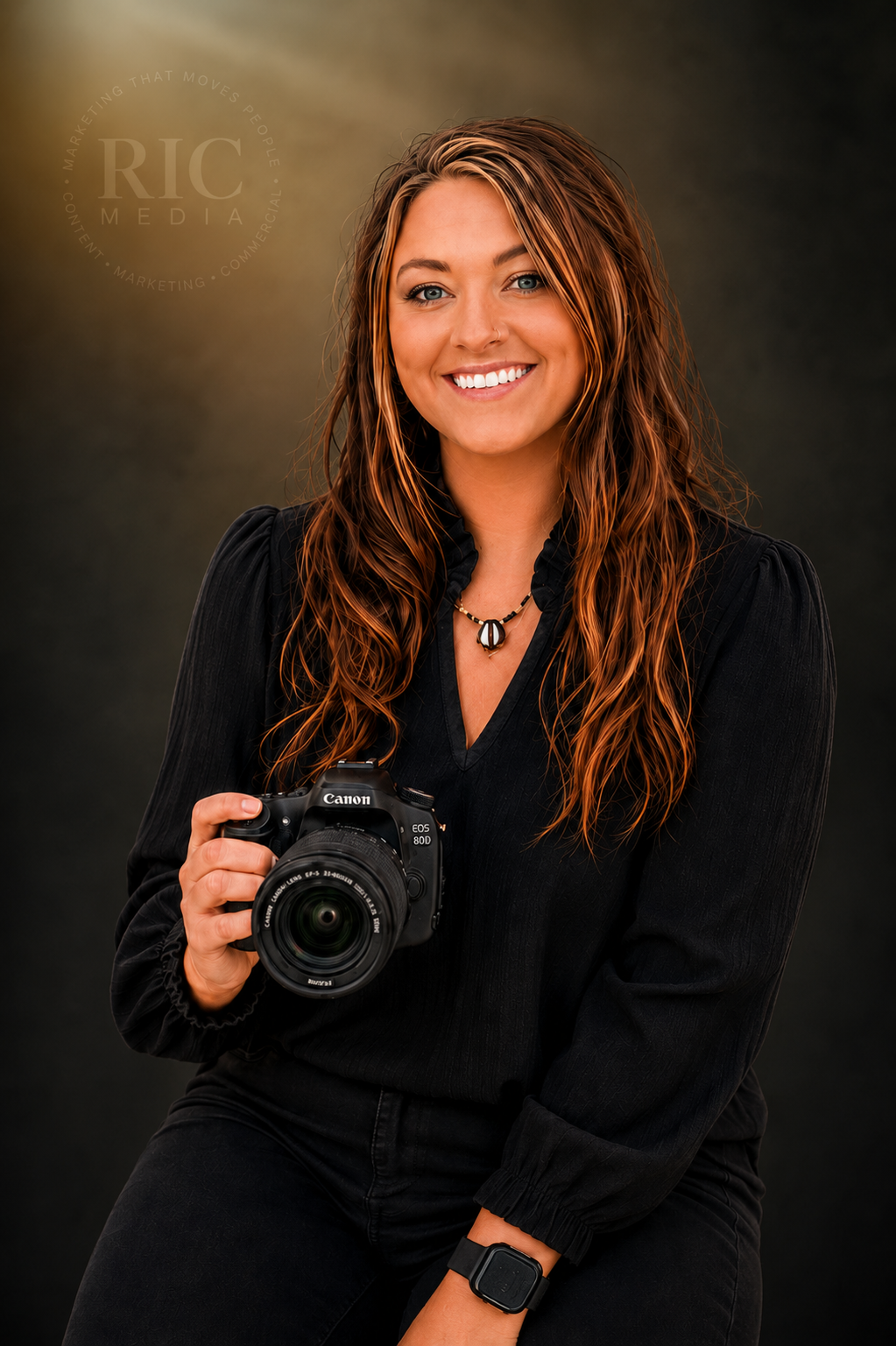 Smiling woman photographer holding a Canon DSLR camera, wearing black outfit with long auburn highlighted hair in studio portrait.