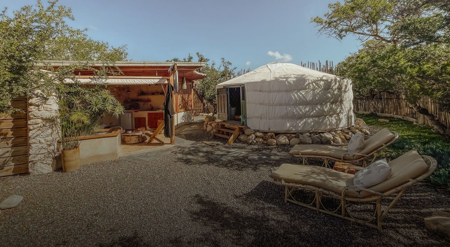 Modern yurt accommodation with wooden deck and outdoor seating area in natural surroundings.