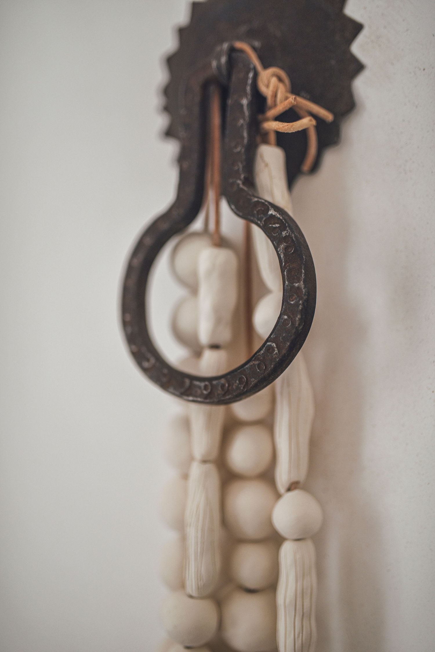 Close-up of decorative white beaded tassel garland hanging from an ornate metal door knocker.
