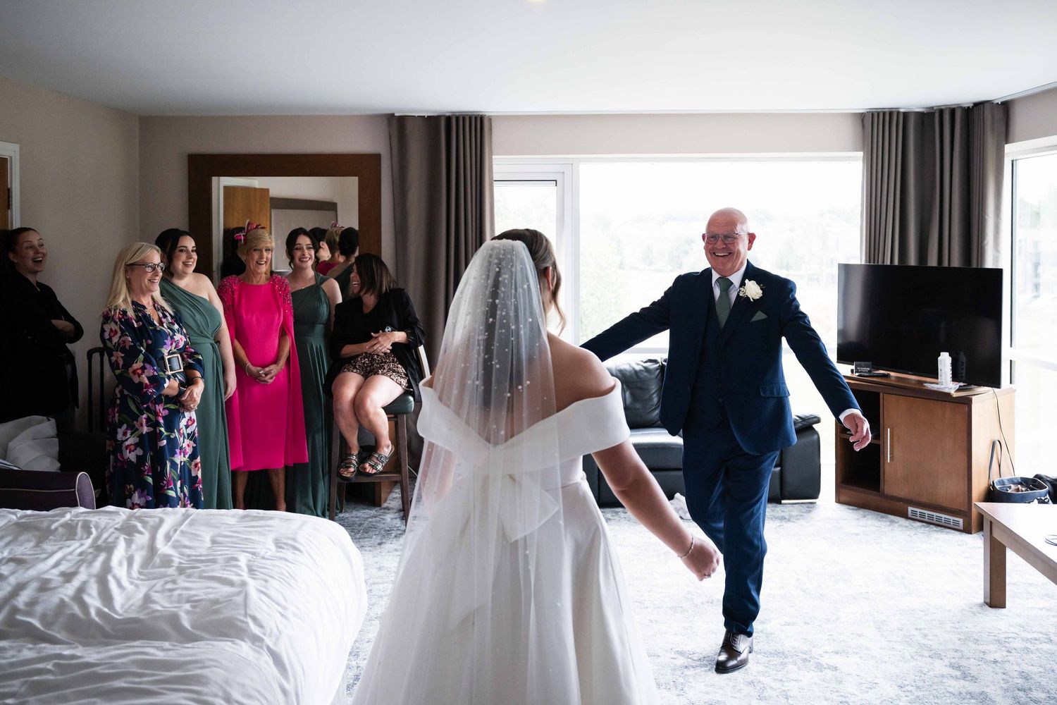 Father walking toward his bride daughter in a hotel room as guests watch the emotional first look. Dunboyne Castle