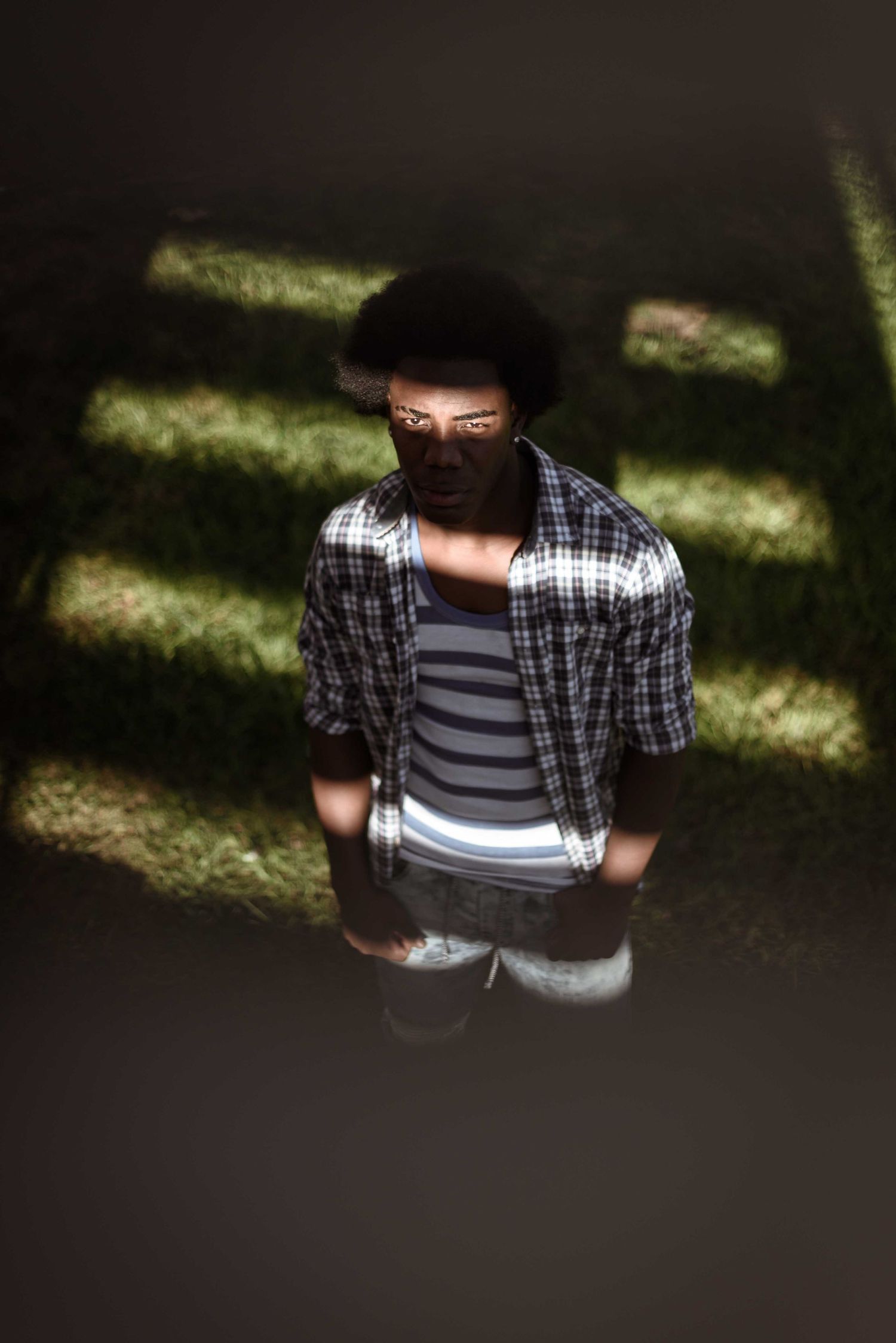 Man in plaid shirt standing in dramatic striped light and shadow outdoors. Portrait Photography Ireland