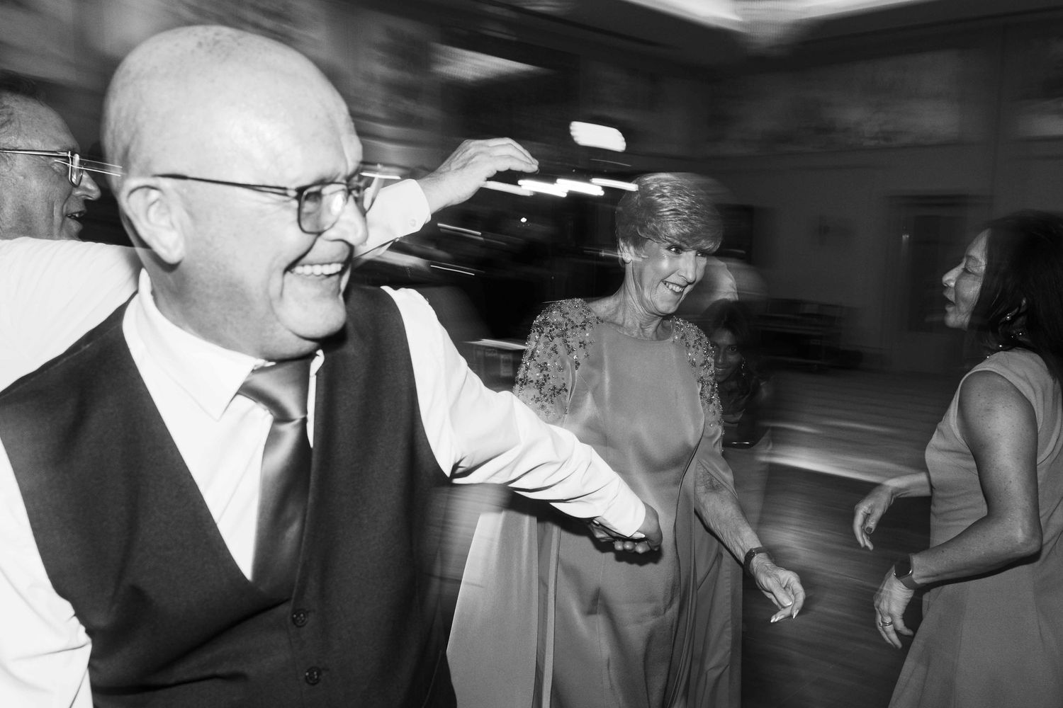 Black and white candid photo of a wedding guest dancing and adjusting glasses at the reception. Irish wedding photography. Dunboyne Castle