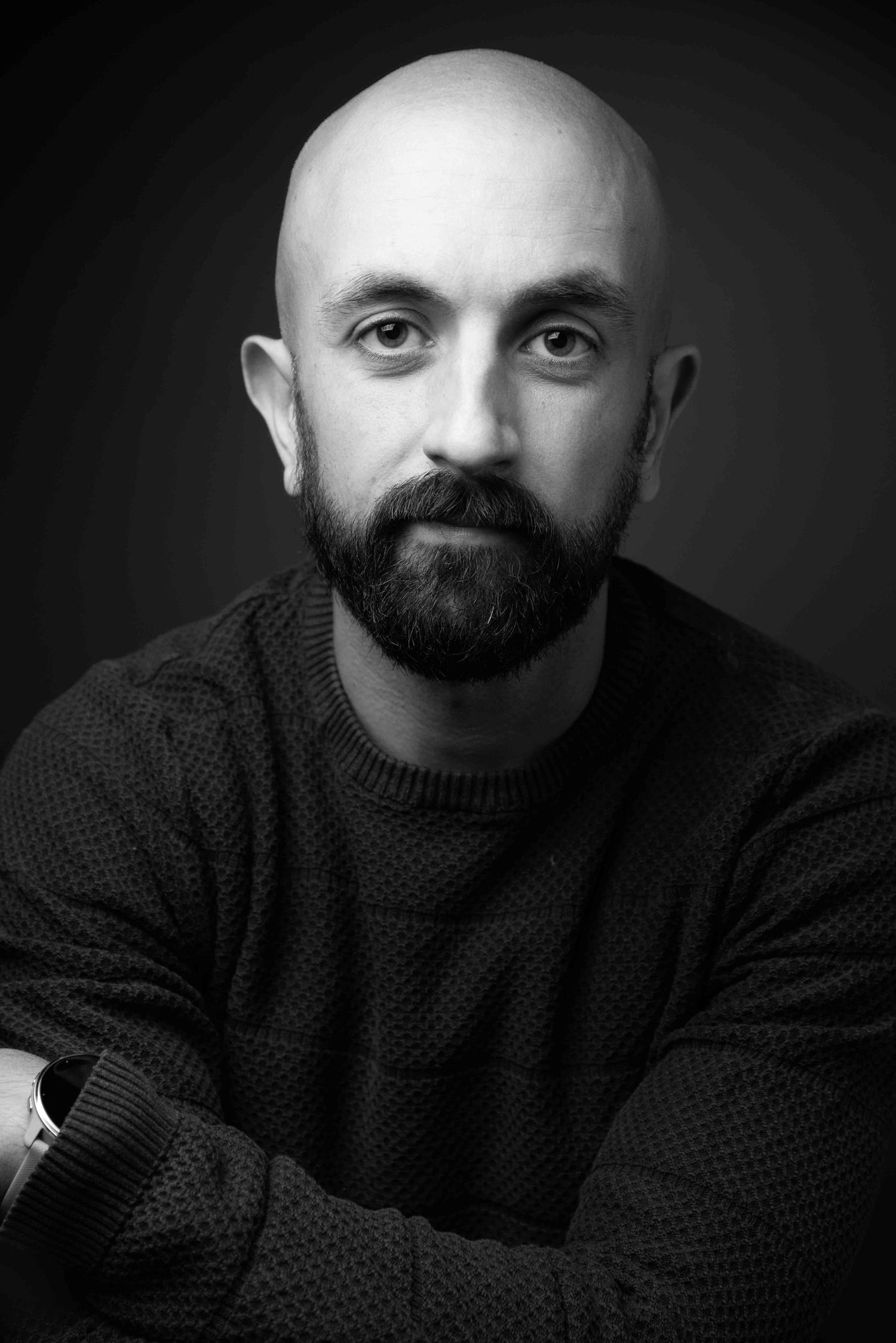 Black and white portrait of a bald bearded man with arms crossed wearing a knit sweater. Portrait Photography Ireland