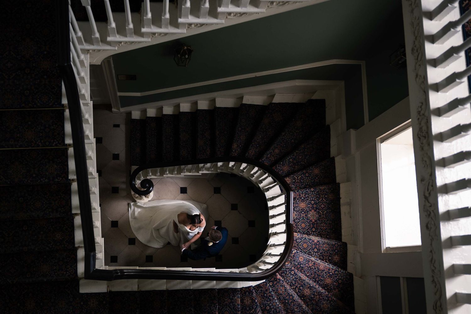 Aerial view of a wedding couple descending an elegant spiral staircase from above. Irish wedding photography. Dunboyne Castle