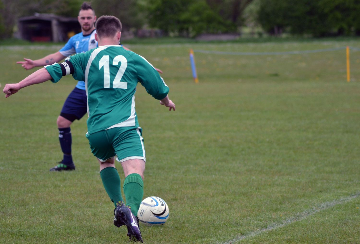 Man in green number 12 shirt about the kick the football.