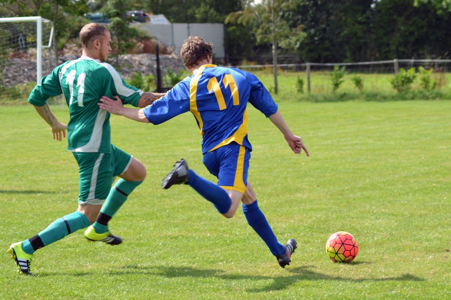 Two men chasing the ball during a game of football.