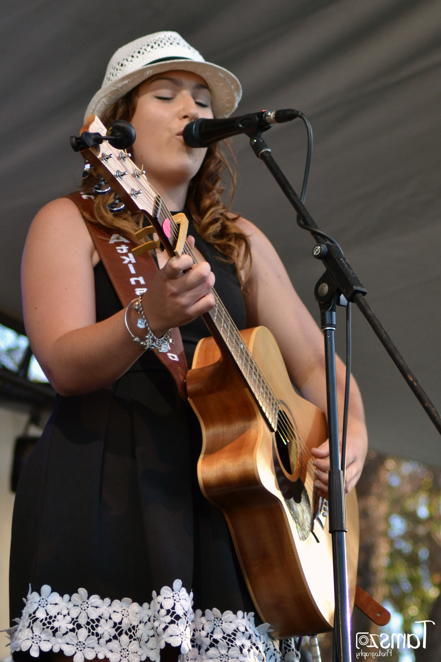 Jasmine Aktins singing at Boyup Brook Country Music festival on stage with her guitar doing an acoustic set.