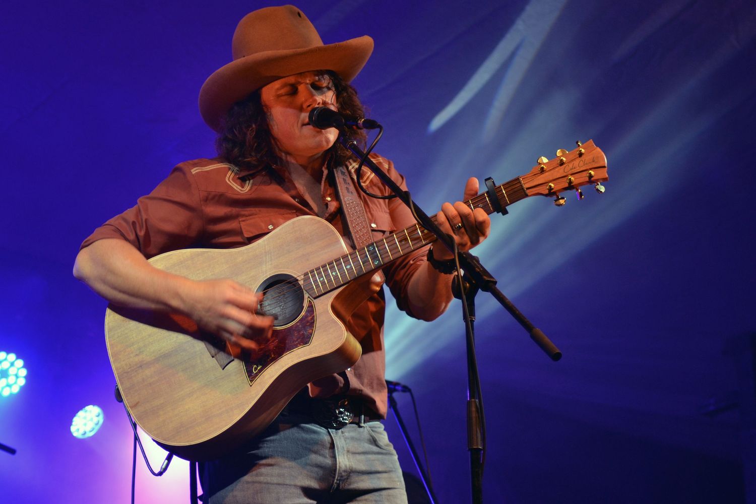 Lead singer of Railway Bell playing his acoustic guitar on stage at Boyup Brook Country Music Festival in Western Australia.