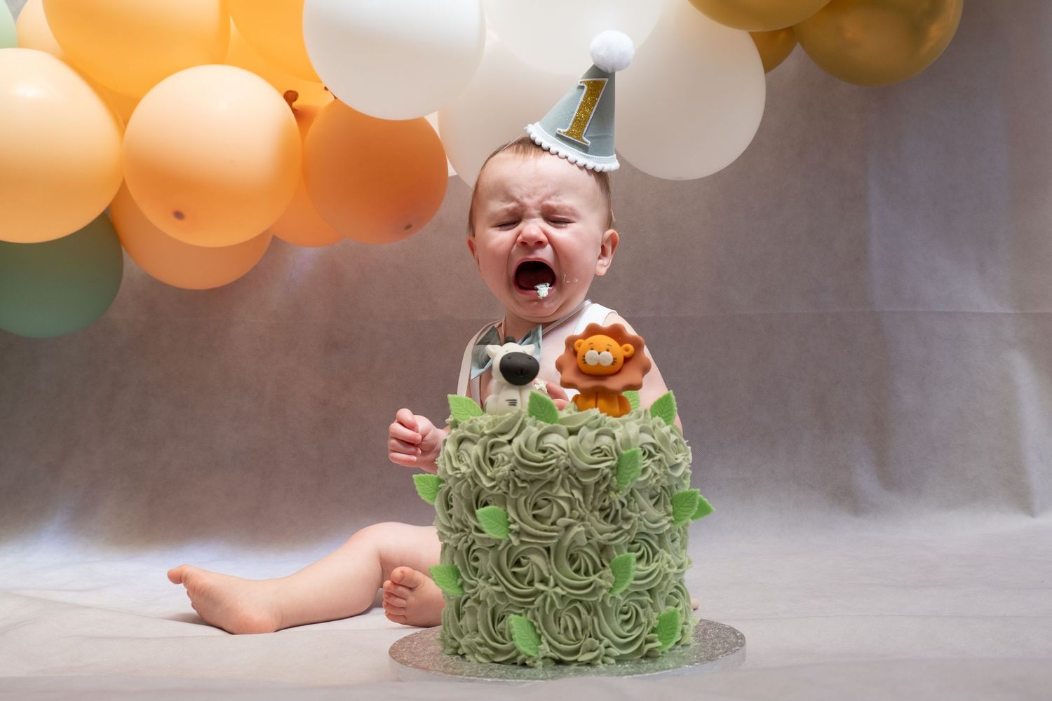Little boy enjoying his first birthday cake smash photoshoot.