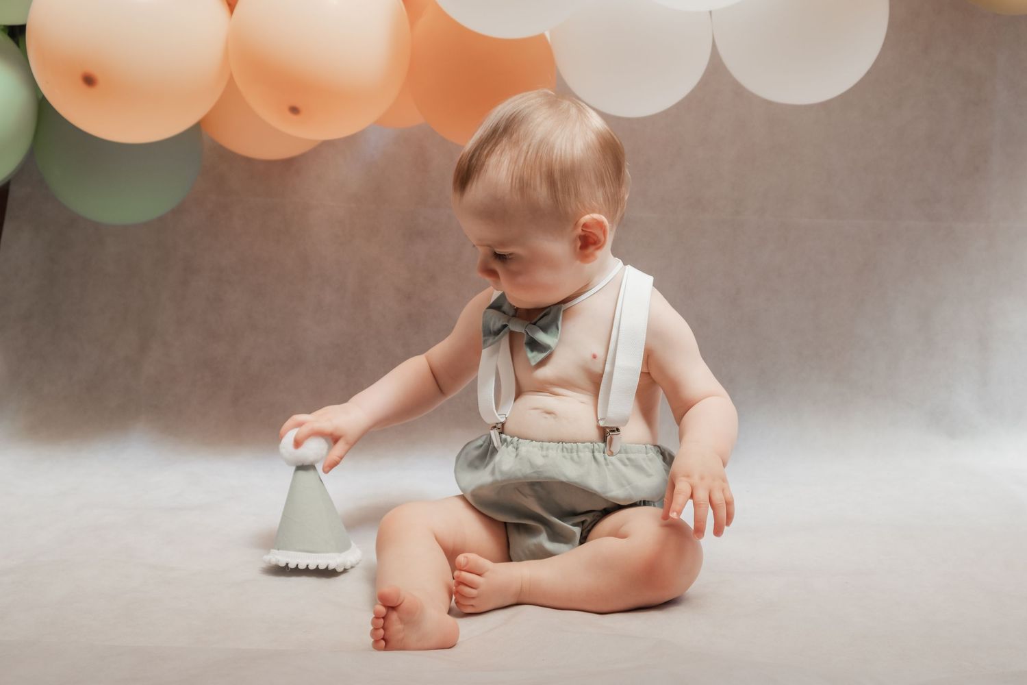 A little boy enjoying his birthday hat during his first birthday photoshoot.