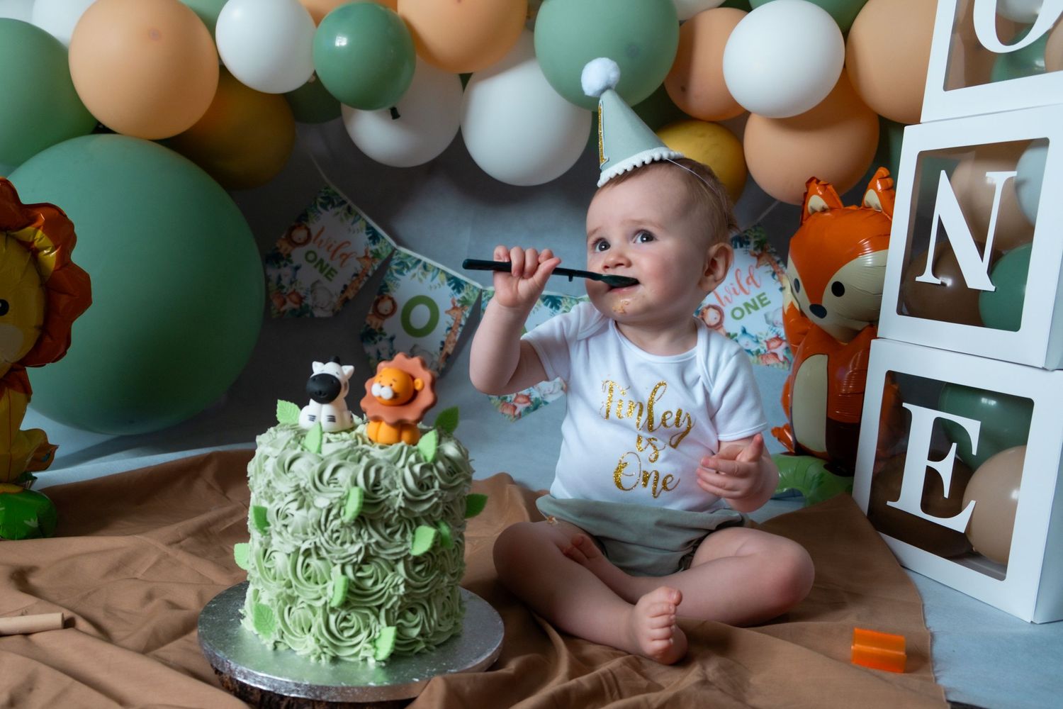 Little boy enjoying his first birthday cake smash photoshoot.