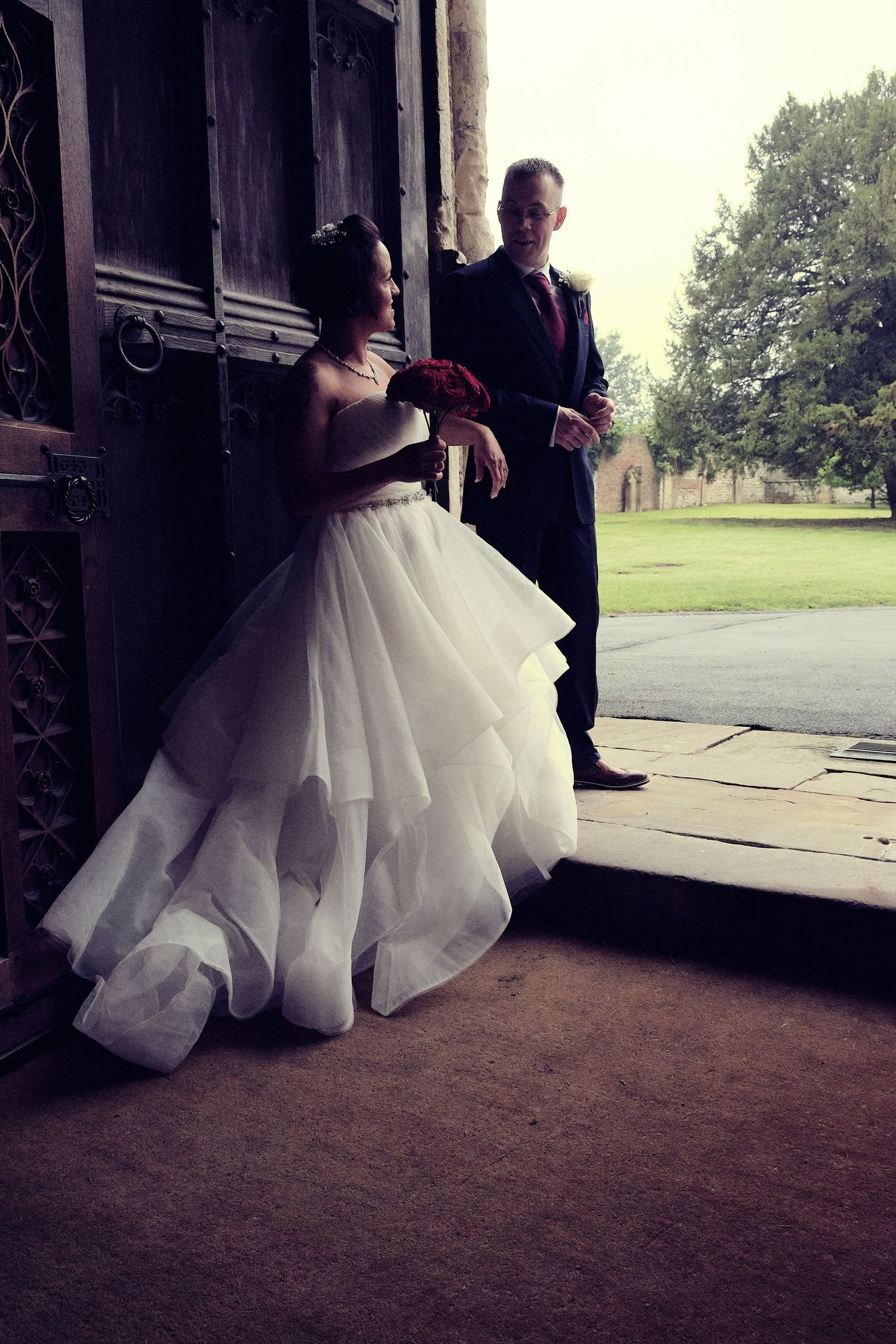 Newly married couple walking hand in hand through the door of the church.