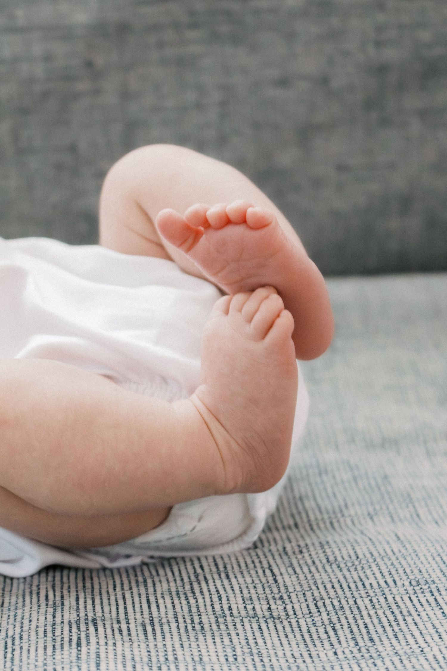 Close-up of adorable newborn baby feet and chubby legs resting on a soft white blanket.