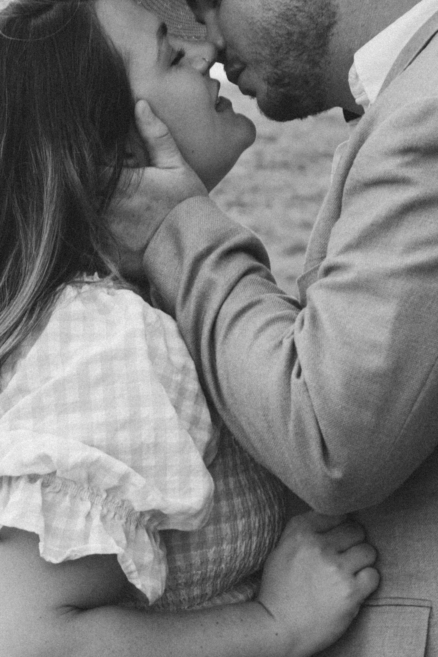Black and white photo of a romantic couple sharing an intimate moment, about to kiss in a tender embrace.