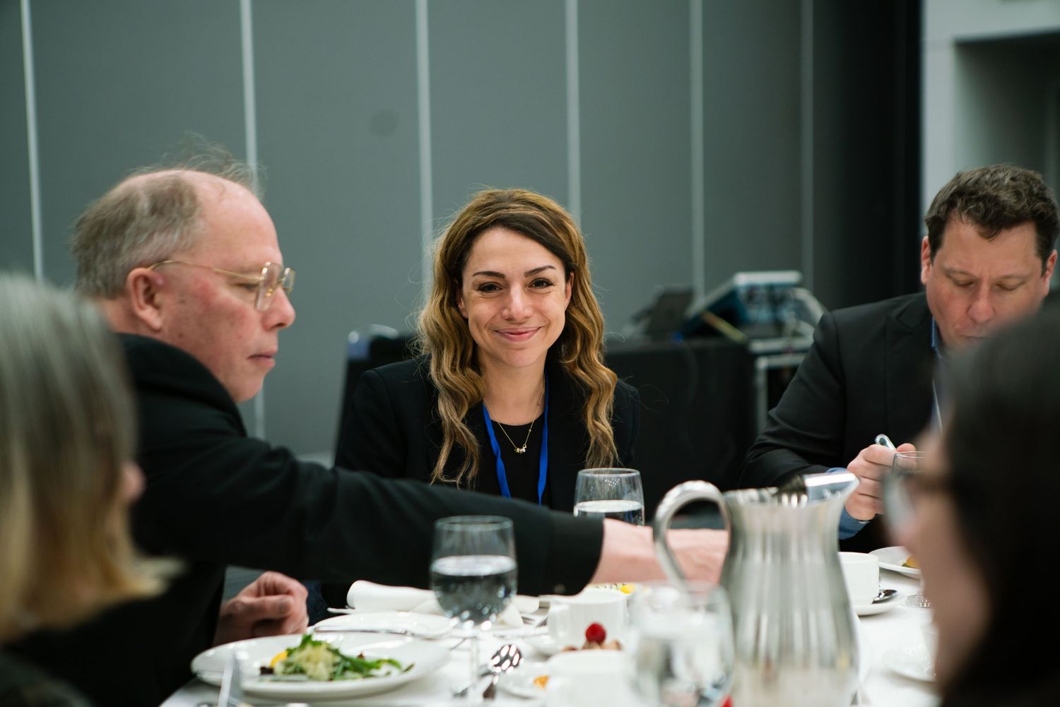 Business colleagues sharing a meal and conversation at a corporate dinner, event photography by HAMIDI Photography.