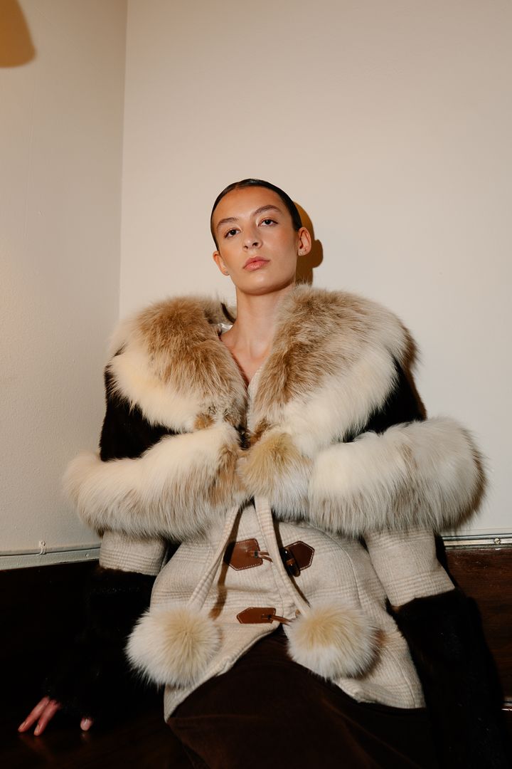 Model in a fur coat posing on the runway under warm lighting, fashion photography by HAMIDI Photography.