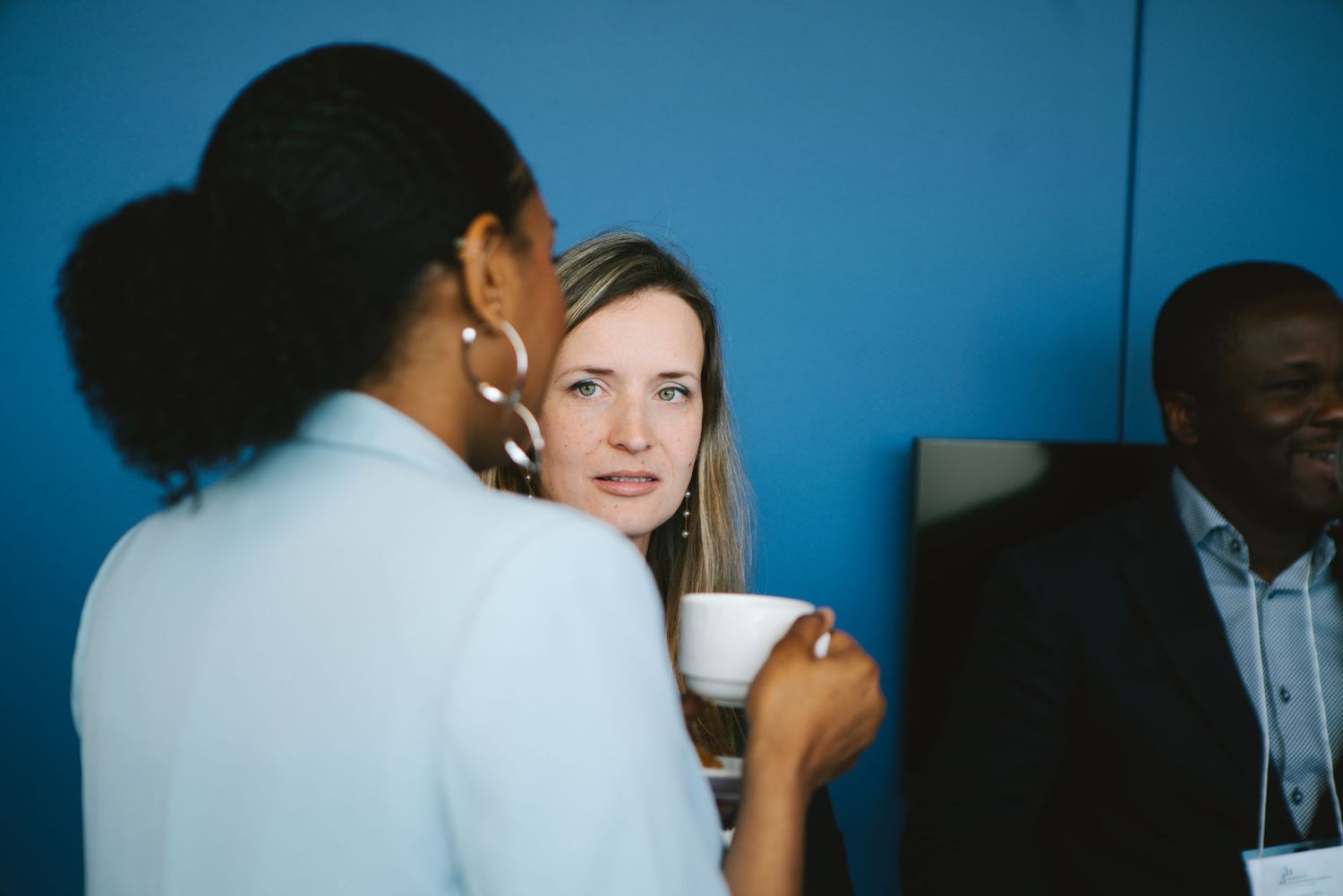 Colleagues in conversation under blue-toned office lighting, corporate photography by HAMIDI Photography.