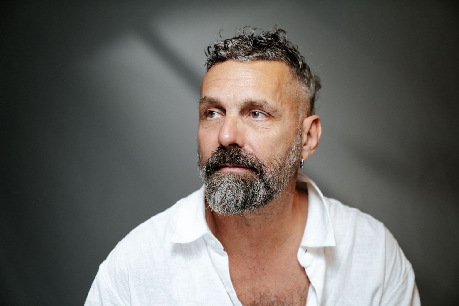 Studio headshot of Bernie Love in a white shirt against a gray backdrop, photography by HAMIDI Photography.