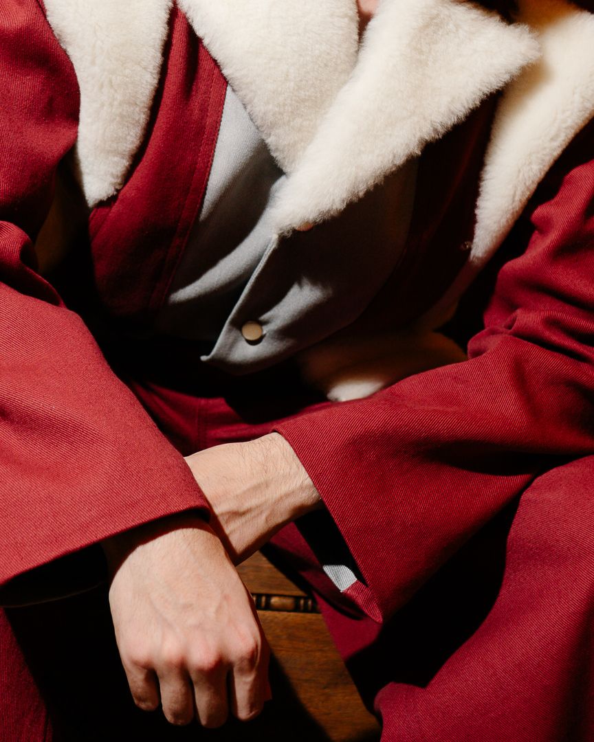 Close-up detail of a model's red and white fur-trimmed sleeve, fashion photography by HAMIDI Photography.