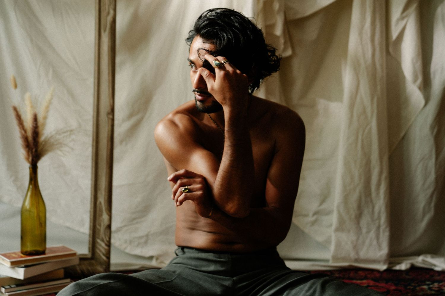 Moody studio portrait of Franco seated with hand raised to his face, photography by HAMIDI Photography.