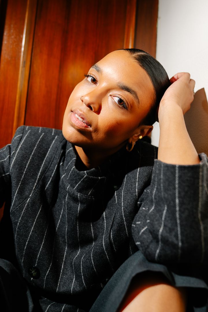 Close-up portrait of a model in black with head tilted under warm lighting, fashion photography by HAMIDI Photography.