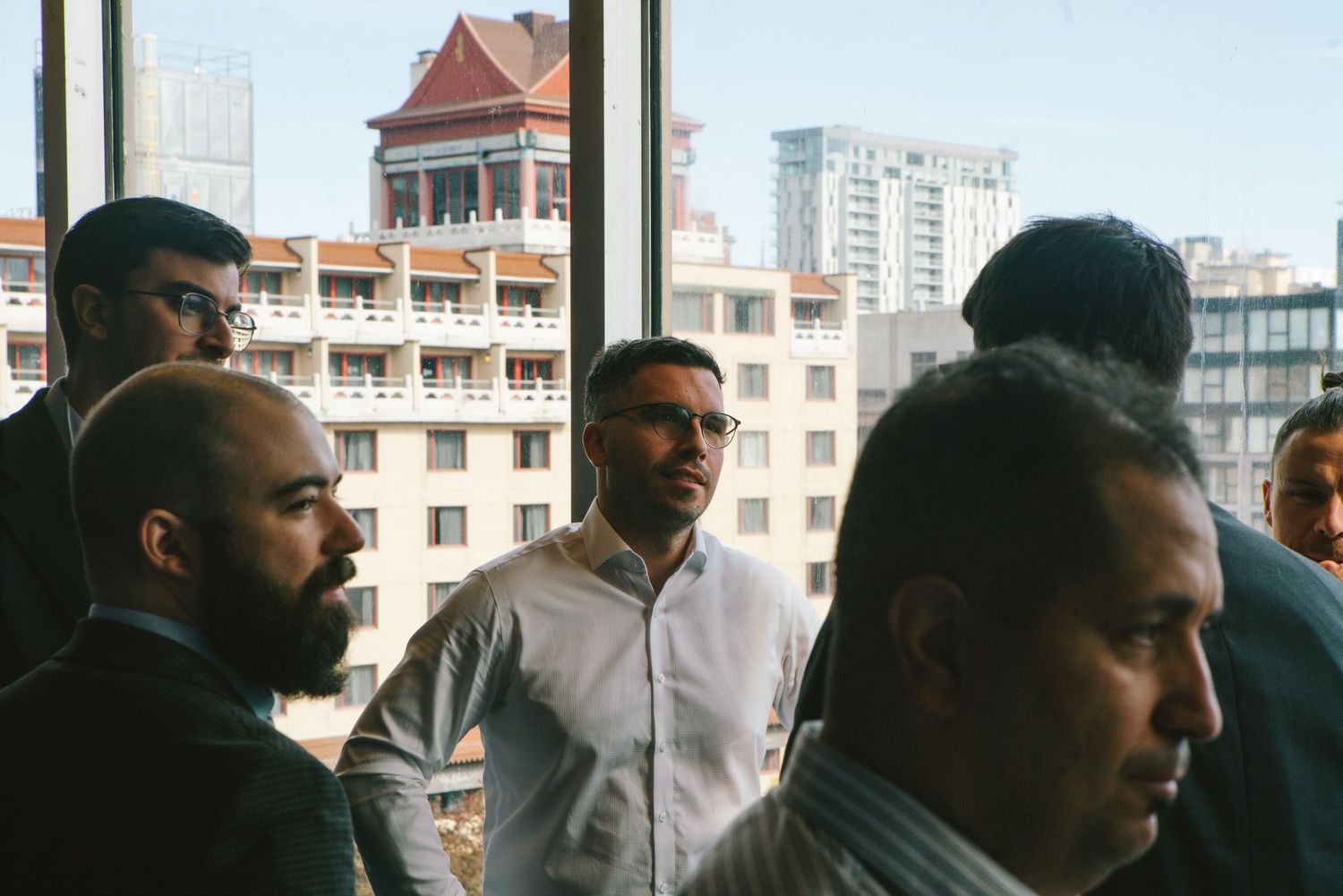 Group of business colleagues in discussion by a window in a modern office, corporate photography by HAMIDI Photography.