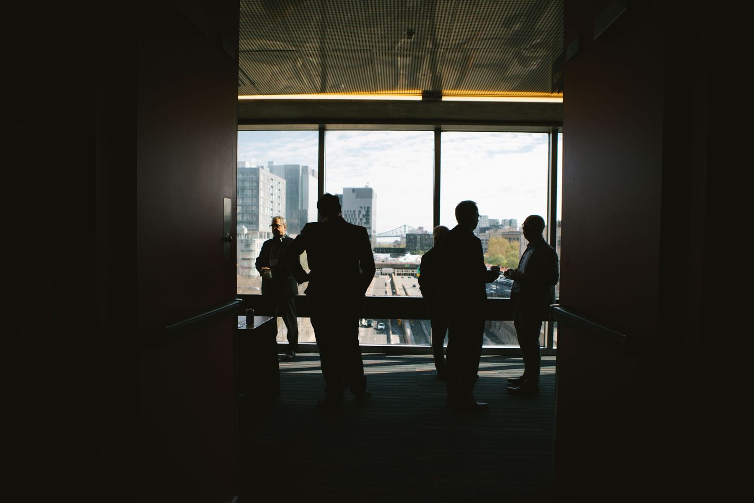 Silhouettes of guests by a window at an evening corporate event, photography by HAMIDI Photography.