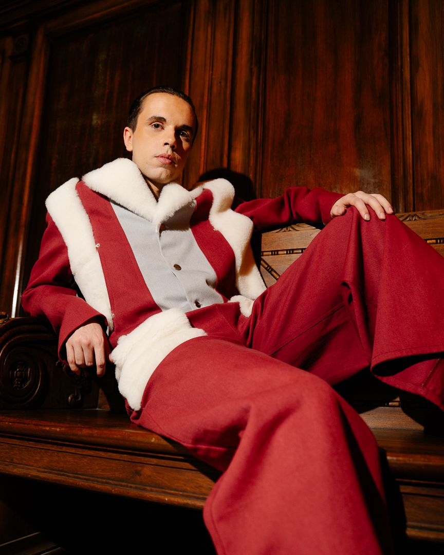 Model seated in a red and white outfit in a warmly lit interior setting, fashion photography by HAMIDI Photography.