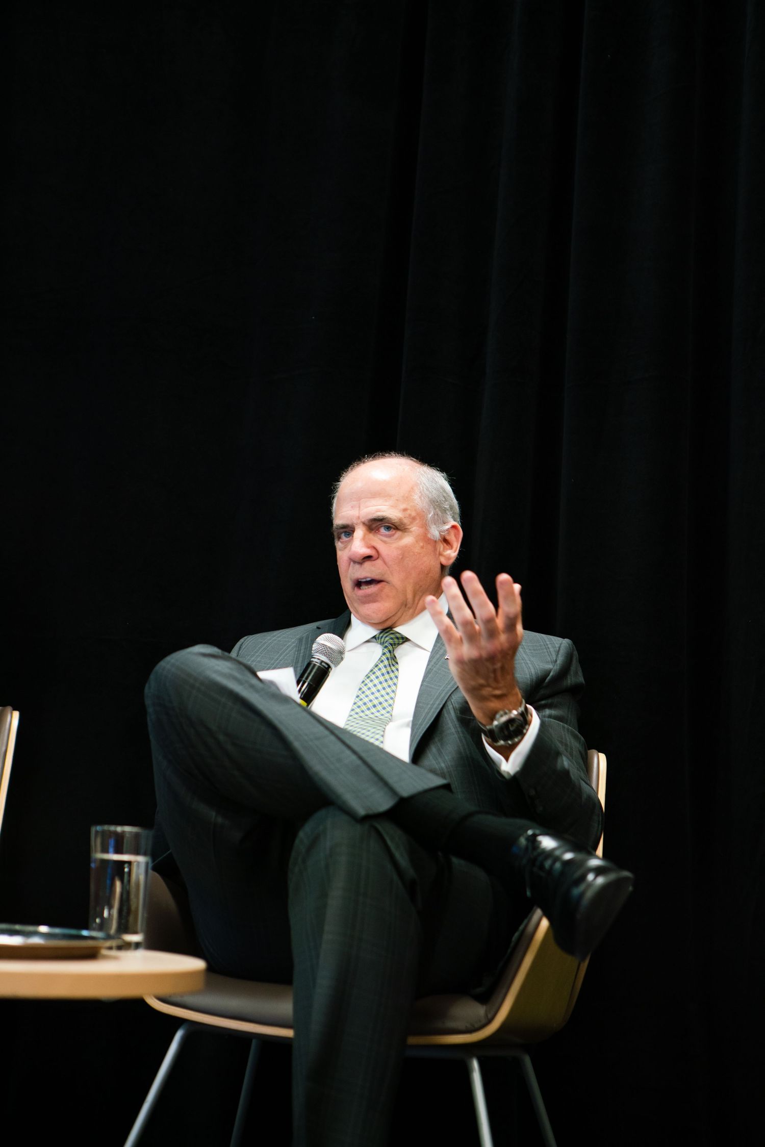 Speaker addressing an audience from a podium in a darkened conference room, event photography by HAMIDI Photography.
