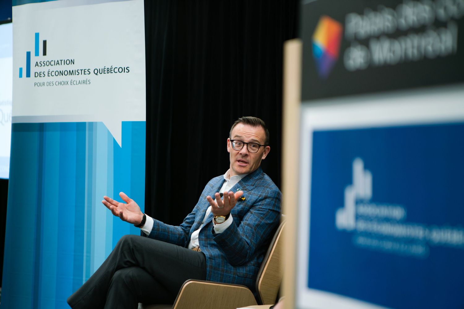 Panelist seated on stage during a corporate conference session, event photography by HAMIDI Photography.