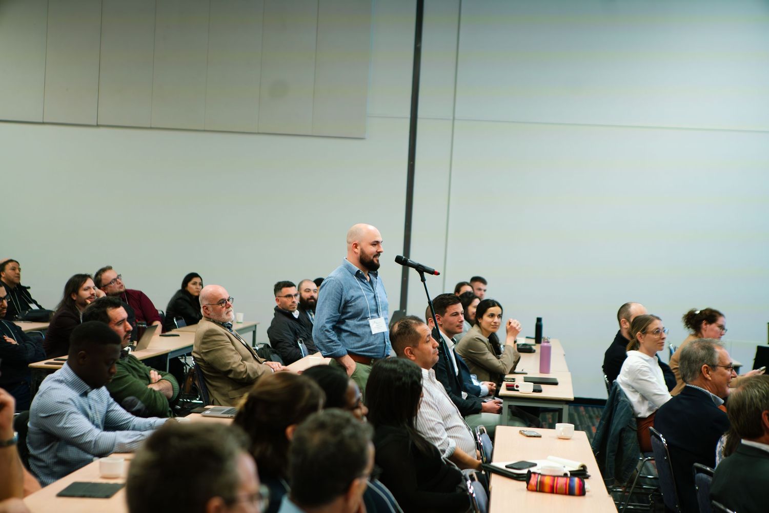 Audience member standing to ask a question during a conference session, event photography by HAMIDI Photography.