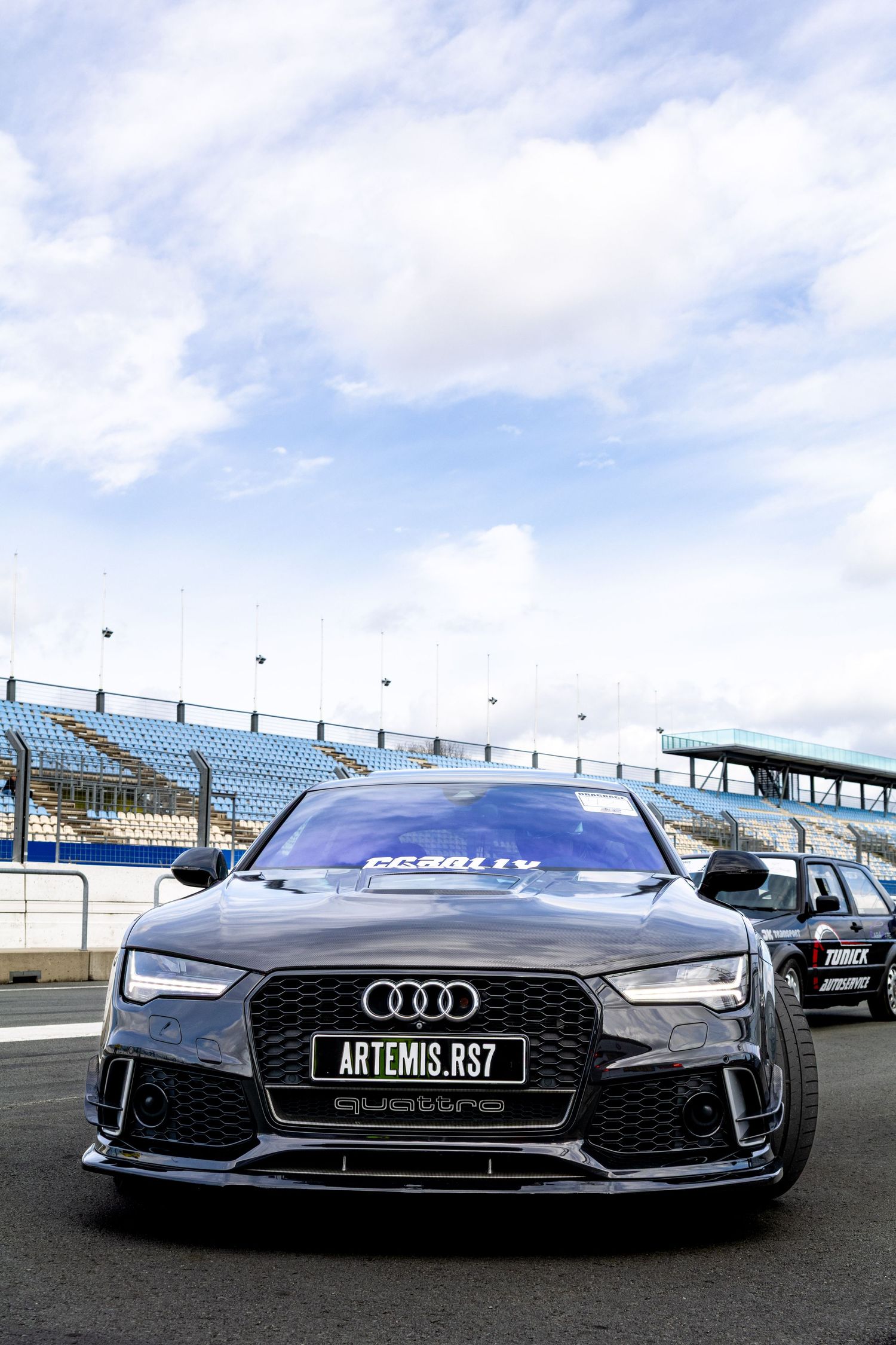 Dark gray Audi RS7 Quattro on a race track, featuring aggressive front styling and Artemis RS7 license plate.