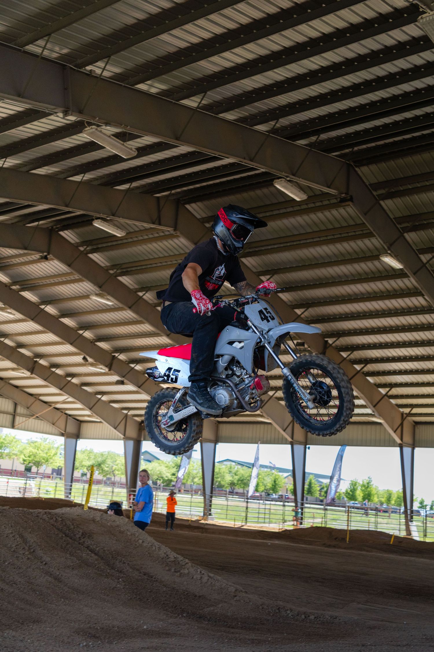Motocross rider number 45 catches air on white dirt bike at indoor supercross track.