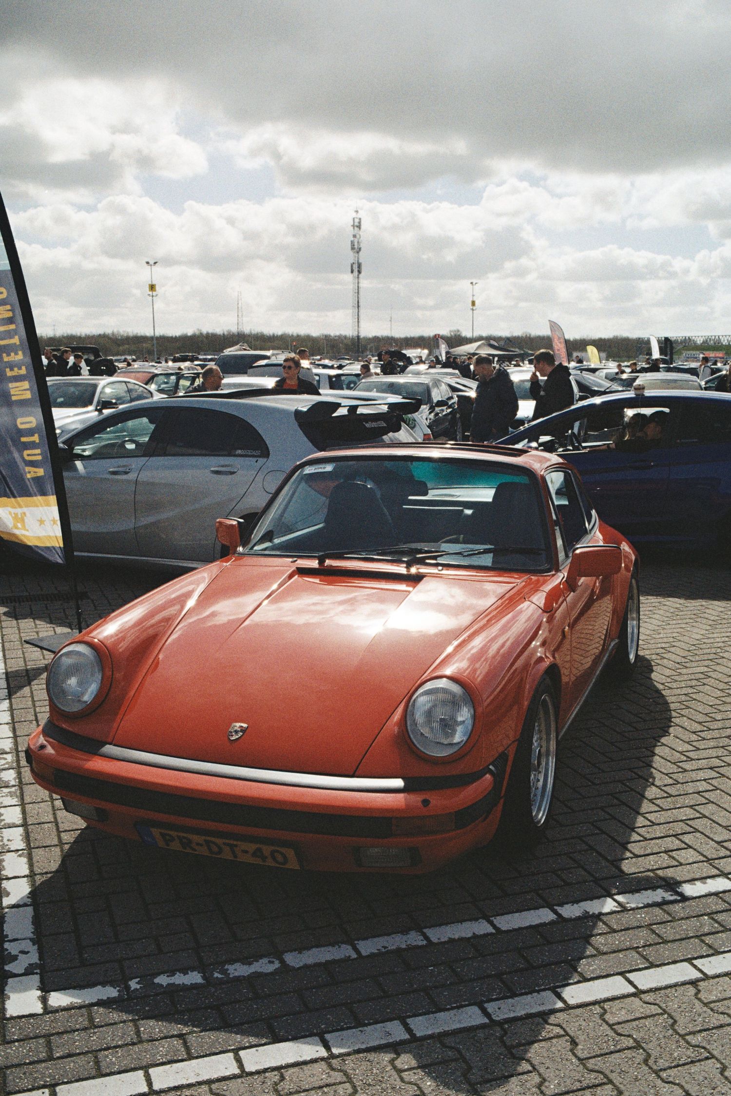 Vintage orange Porsche 911 displayed at an outdoor classic car meeting event.
